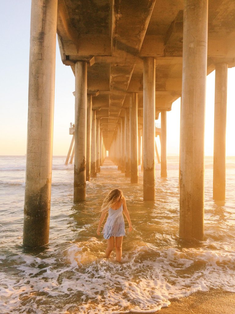 A woman at the beach under a pier